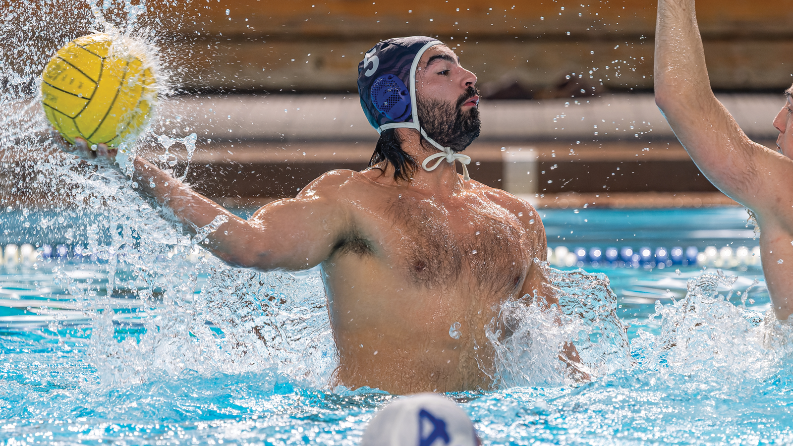 Toronto men's water polo player jumping in the water to shoot the ball