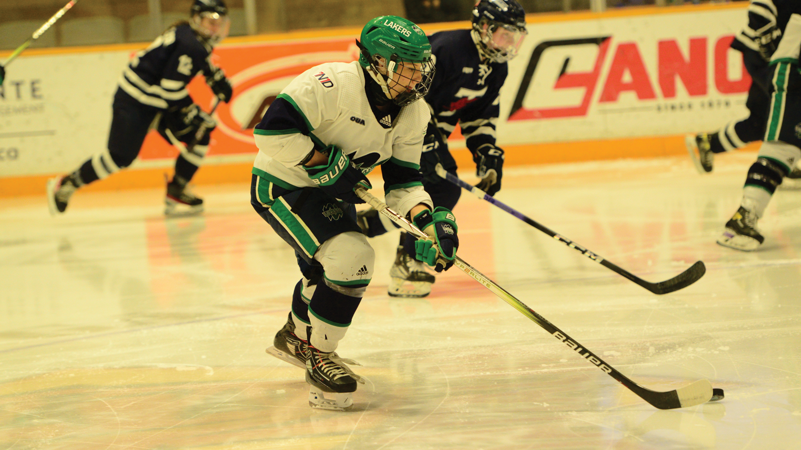 Nipissing women's hockey player Katie Chomiak skating on the ice with the puck on her stick