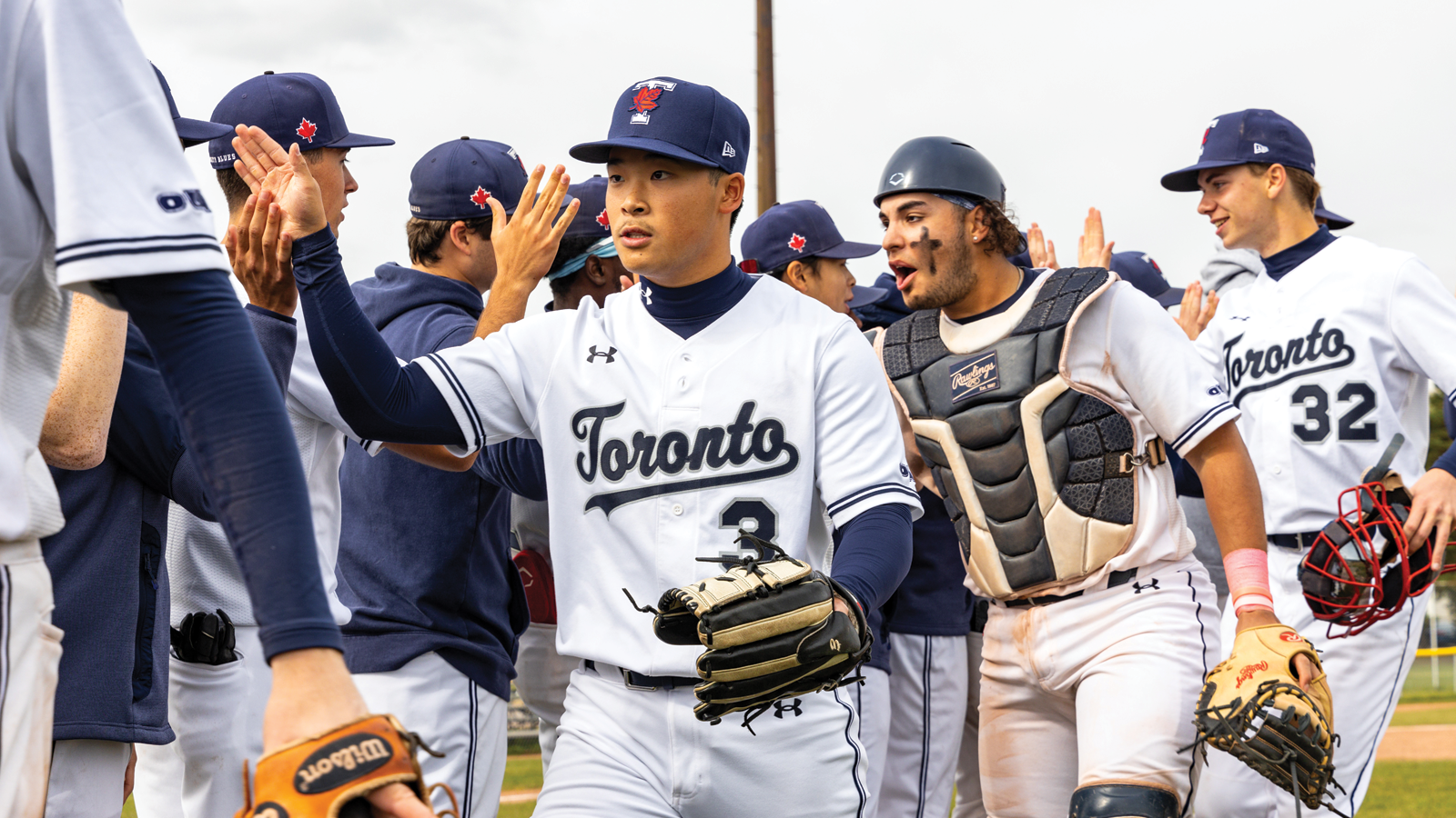 Toronto Varsity Blues baseball team in two opposite facing lines high fiving each other after the game