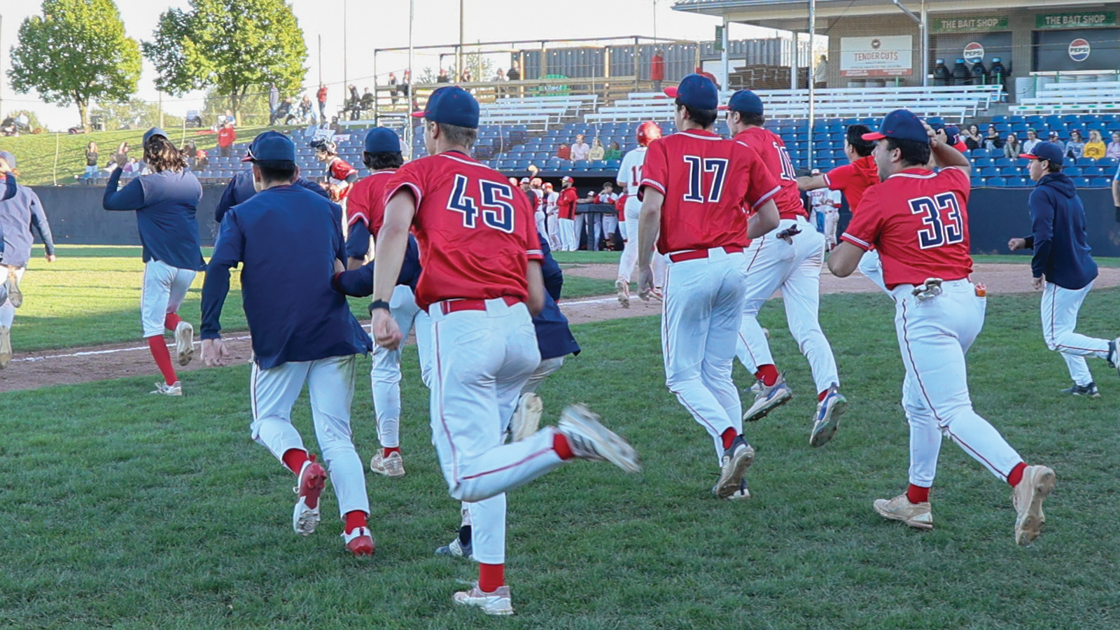 Action photo of the Brock men's baseball team celebrating their win - running towards the mound