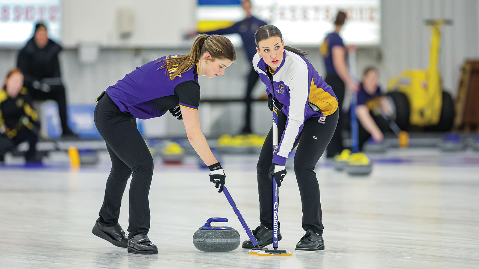 Action photo of the two Laurier women's curlers sweeping the rock 