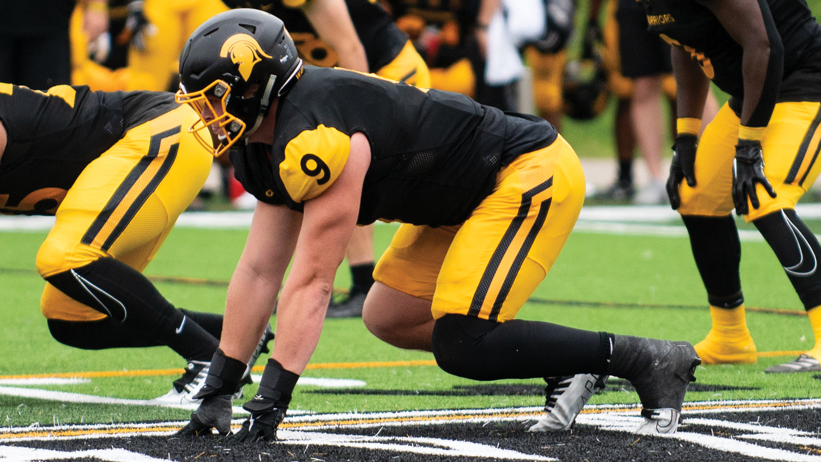Waterloo football player Tyson Hergott in the ready position on the line during a game