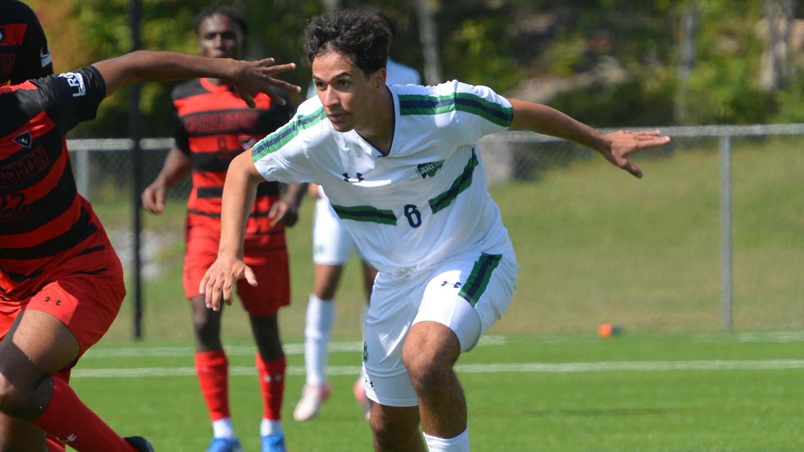 Nipissing men's soccer player running toward the ball with an opposing Carleton player doing the same