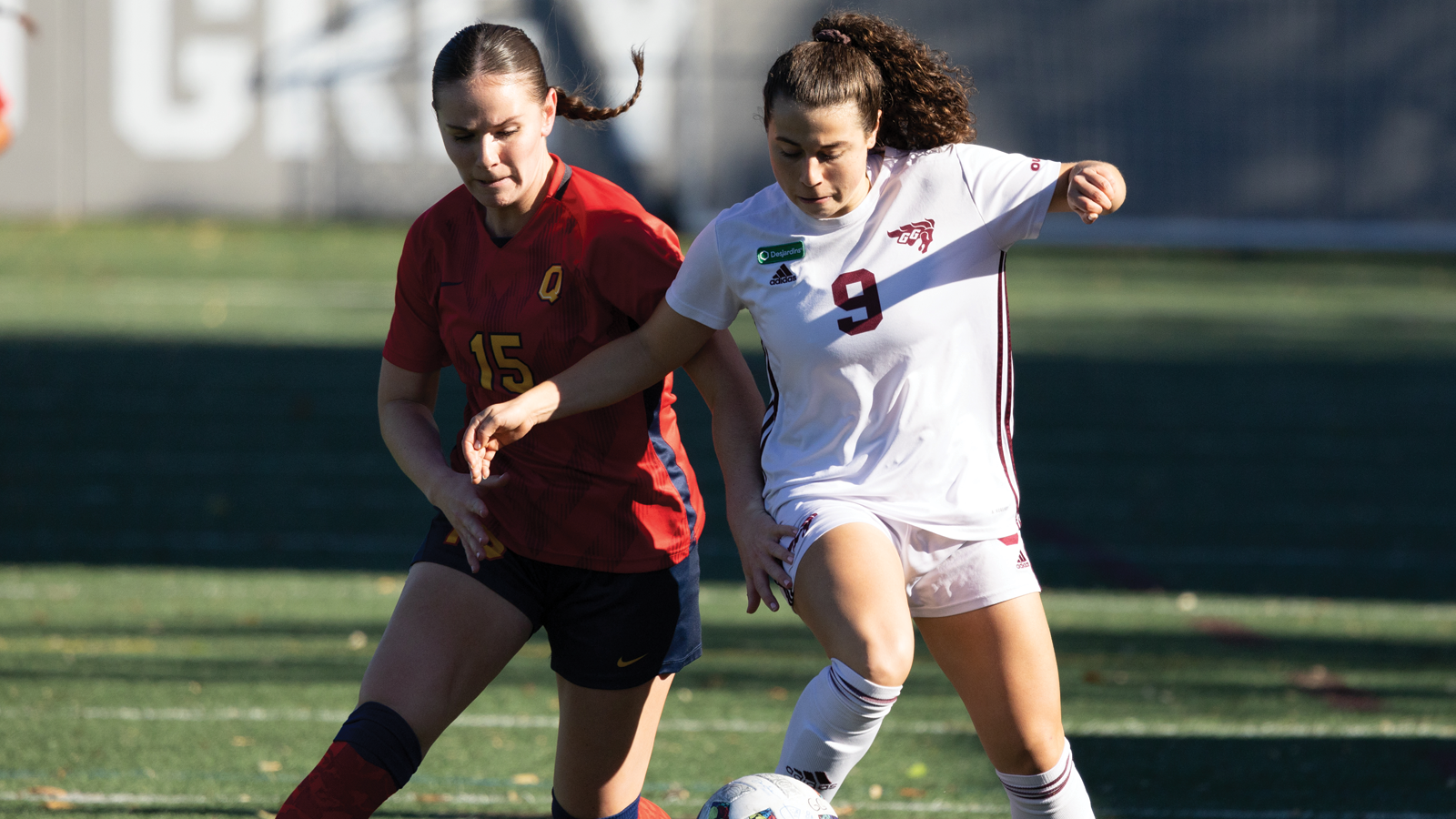 An Ottawa and Queen's women's soccer player competing for the ball during a game