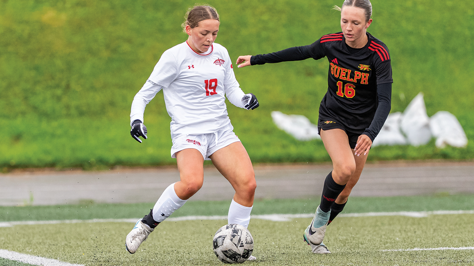 Action photo of Yvonne Barnes from the Algoma Thunderbirds women's soccer team about to kick the ball 
